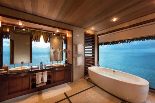 a bathroom with two sinks and a tub and a large window at Conrad Bora Bora Nui in Bora Bora