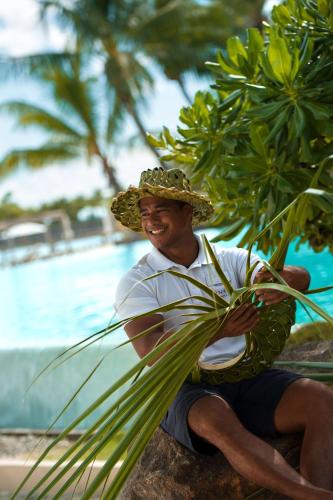 a man wearing a straw hat sitting next to a pool at Conrad Bora Bora Nui in Bora Bora