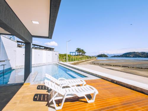 una casa con una piscina con sillas blancas en VELINN Angra Sunset Hotel & Villas, en Angra dos Reis