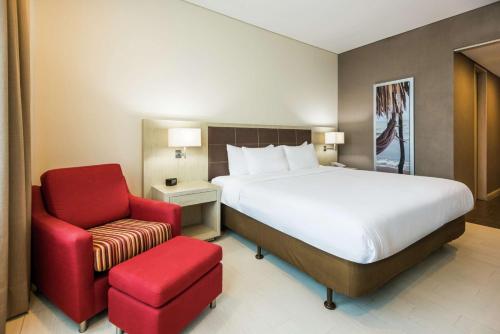 um quarto com uma cama e uma cadeira vermelha em Hilton Garden Inn Barranquilla em Barranquilla