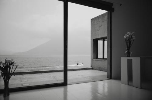 a room with a view of the ocean through a window at Anzan Atitlan in San Marcos La Laguna
