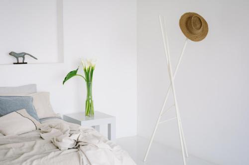 a white bedroom with a bed and a vase of flowers at Anzan Atitlan in San Marcos La Laguna