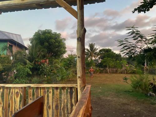 una persona in piedi in un cortile accanto a una recinzione di legno di Rocky Homestay Lakey a Huu