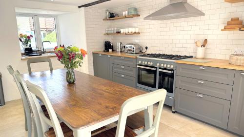 a kitchen with a wooden table with a vase of flowers at Beautiful Rural Cottage by the Coast in East Portlemouth