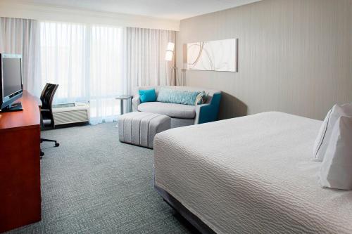 um quarto de hotel com uma cama e uma cadeira em Courtyard by Marriott Ann Arbor em Ann Arbor