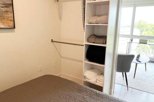 a bedroom with a bed and a book shelf with a television at Modern Queen Bed & Twin Futon Studio with WiFi, Kitchen, Washer, and Dryer in Charlotte