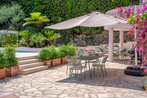 un patio avec une table, des chaises et un parasol dans l'établissement CLR - Stunning renovated house with pool to rent, au Cannet