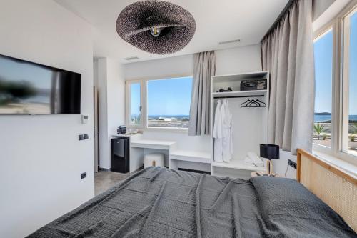 a bedroom with a bed and a desk and windows at NOS Suites in Ermoupoli