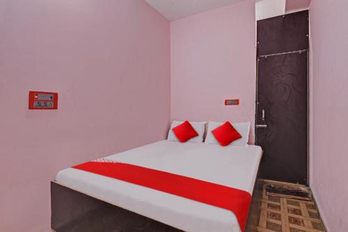 um quarto com uma cama branca e almofadas vermelhas em Flagship Red Rose Hotel & Banquet em Dhanbad