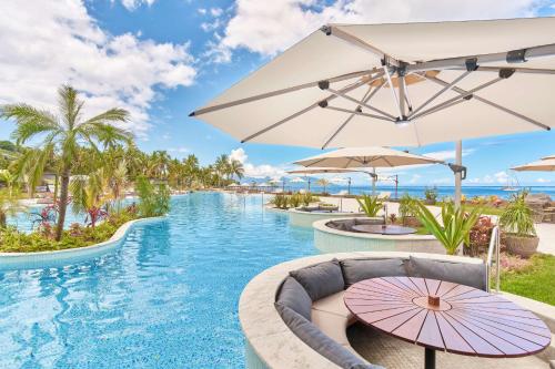 a pool at the resort with umbrellas at Hilton Hotel Tahiti in Papeete