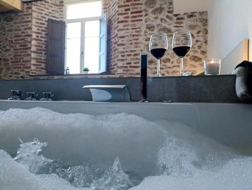 two glasses of wine in a bathtub with water at El Esquileo in Buitrago del Lozoya