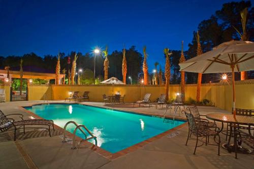 a swimming pool with tables and chairs at night at Hampton Inn & Suites North Charleston-University Boulevard in Charleston