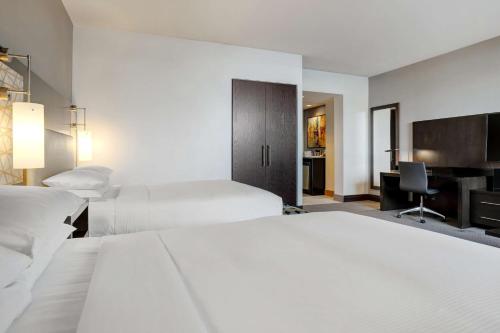 a hotel room with two beds and a desk at Hilton Dallas/Plano Granite Park in Plano