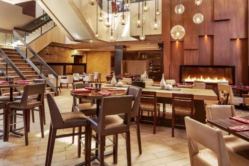 restauracja ze stołami i krzesłami oraz kominkiem w obiekcie Hilton Denver City Center w mieście Denver