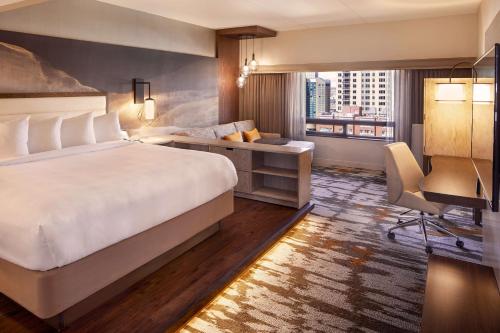 a hotel room with a bed and a desk and a window at Hilton Denver City Center in Denver