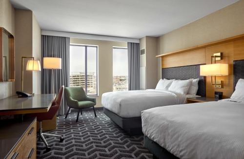 德梅因Hilton Des Moines Downtown的有两张床和一张书桌的酒店房间