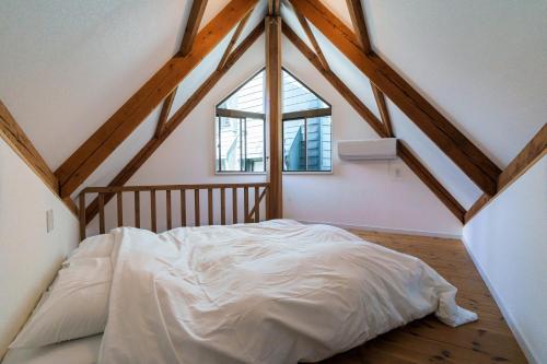 a bedroom with a white bed in a attic at 野沢温泉ロッヂ in Nozawa Onsen