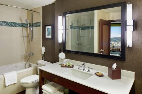 a bathroom with a sink and a toilet and a mirror at DoubleTree by Hilton Alana - Waikiki Beach in Honolulu
