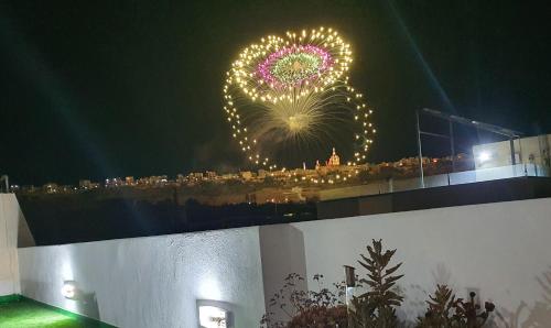 a firework display at night with a city in the background at Millennium Penthouse with private Hot Tub Gozo in Għajnsielem