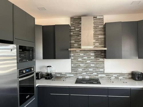 a kitchen with black cabinets and a brick wall at Colinas Casa en la Playa in Puerto Peñasco