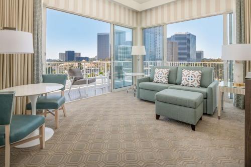 a living room with chairs and a table and large windows at The Beverly Hilton in Los Angeles