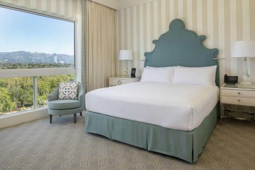 a bedroom with a large bed and a large window at The Beverly Hilton in Los Angeles