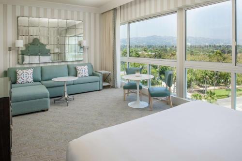 a living room with a couch and tables and windows at The Beverly Hilton in Los Angeles