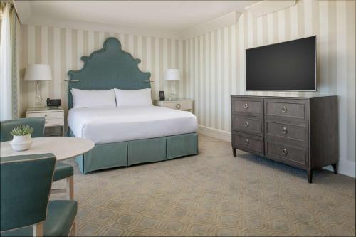 a hotel room with a bed and a flat screen tv at The Beverly Hilton in Los Angeles