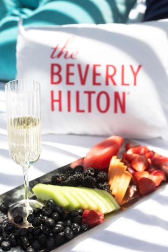 a plate of fruit next to a glass of wine at The Beverly Hilton in Los Angeles