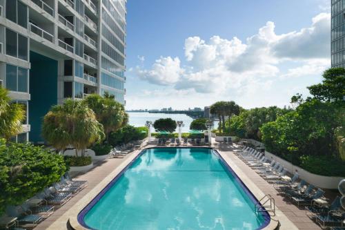 einen Pool in einem Hotel mit Stühlen und einem Gebäude in der Unterkunft DoubleTree by Hilton Grand Hotel Biscayne Bay in Miami