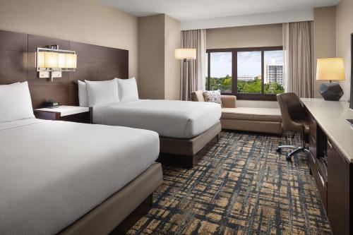 a hotel room with two beds and a desk at Hilton Orlando Lake Buena Vista - Disney Springs™ Area in Orlando