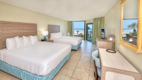a hotel room with two beds and a balcony at El Caribe Resort and Conference Center in Daytona Beach