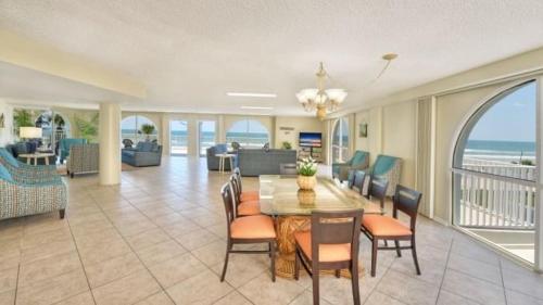 een woonkamer met een tafel en stoelen en de oceaan bij El Caribe Resort and Conference Center in Daytona Beach