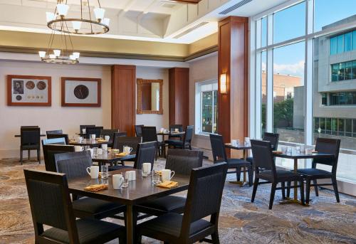 a restaurant with tables and chairs and large windows at The Inn at Penn, A Hilton Hotel in Philadelphia