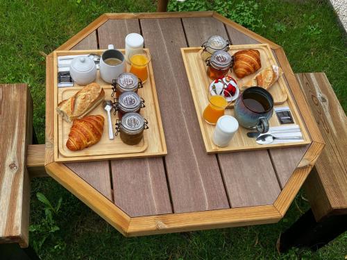 une table en bois avec deux assiettes de nourriture et de croissants dans l'établissement Échappée Enchantée dans une Ancienne Gare au Bord de la Forêt d'Orléans - FR-1-590-268, à Combreux