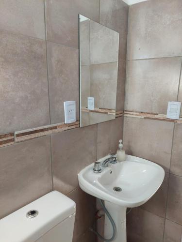 a bathroom with a sink and a mirror and a toilet at Loma Alta Apart in Villa Yacanto