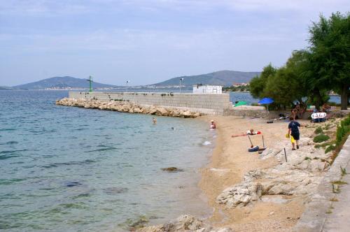 a sandy beach with people on it next to the water at Apartments by the sea Sepurine, Prvic - 4237 in Prvić Šepurine