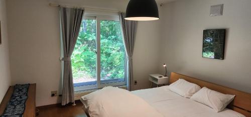 a bedroom with a white bed and a large window at El Cosmo Lodge, Niseko in Niseko