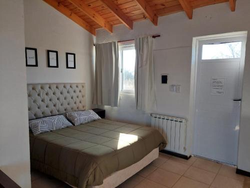 Un dormitorio con una cama grande y una ventana en Loma Alta Apart en Villa Yacanto