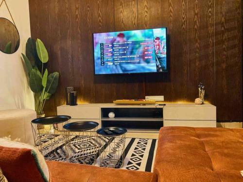a living room with a couch and a flat screen tv at Roswell Luxury Properties Yaoundé - Quartier FOUDA in Yaoundé