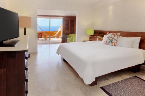 a bedroom with a large white bed and a television at Las Brisas Ixtapa in Ixtapa