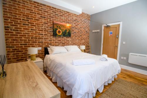 a bedroom with a white bed with a brick wall at Tavmar Accommodation in Lincoln