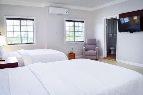 a white room with two beds and a tv at JamGolia Place in Mandeville