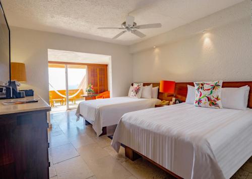 a hotel room with two beds and a balcony at Las Brisas Ixtapa in Ixtapa