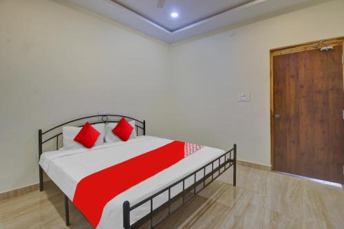 1 dormitorio con cama con almohadas rojas y puerta de madera en OYO Flagship Hotel Vathsalya, en Warangal