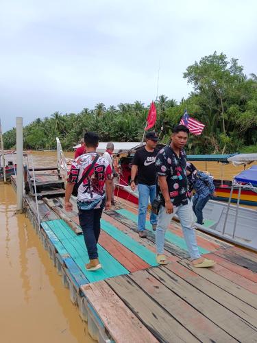 a group of men walking across a wooden bridge at Homestay Anjung Ismail Anjung Rahmah in Kampong Pauh