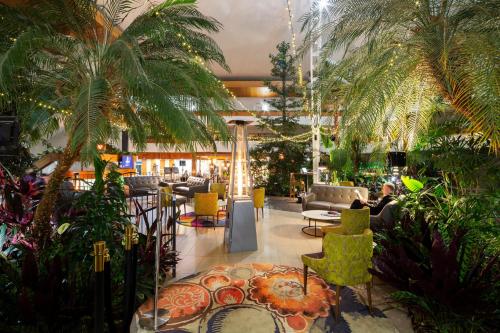 a lobby with palm trees and chairs and tables at Pavilion On Northbourne in Canberra