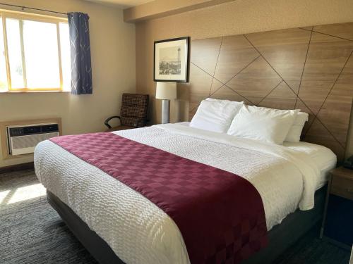 a hotel room with a large bed with a purple blanket at Americas Best Value Inn Lynnwood in Lynnwood