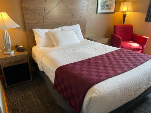 リンウッドにあるAmericas Best Value Inn Lynnwoodのベッドと赤い椅子が備わるホテルルームです。