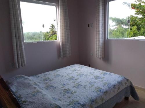 ein Schlafzimmer mit einem Bett in einem Zimmer mit zwei Fenstern in der Unterkunft Casa do Sossego Guarajuba Barra do Jacuípe in Camaçari